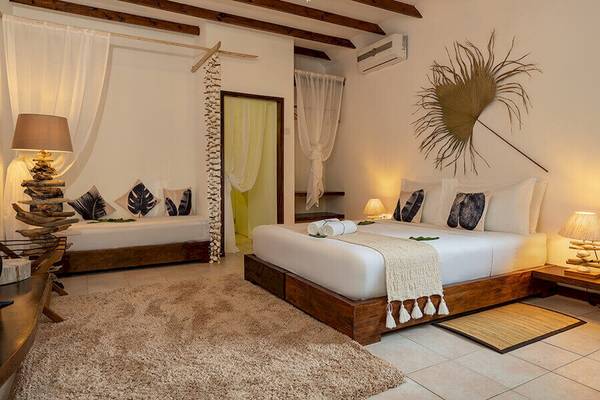Schlafzimmer im Bliss Hotel Praslin mit zwei Betten, Lampen und Dekor.