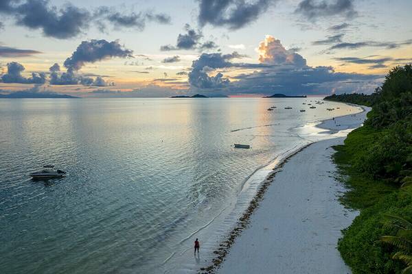 Strand auf Praslin bei Sonnenuntergang mit weißen Sand und grüner Vegetation