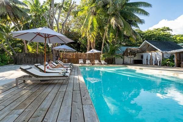 Pool mit Sonnenliegen und Sonnenschirmen im Bliss Hotel Praslin
