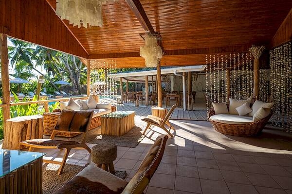 Loungebereich im Bliss Hotel Praslin mit rustikalem Design und Blick auf den Pool.