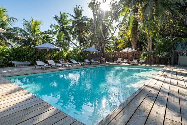 Außenpoolbereich des Bliss Hotel Praslin mit Loungestühlen und Sonnenschirmen