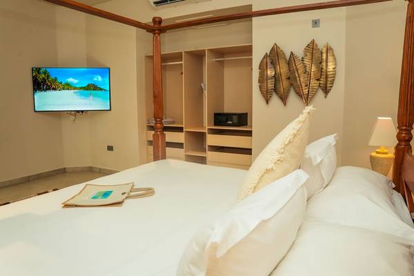 Schlafzimmer im Le Duc de Praslin Hotel mit Bett, Fernseher und Lampe