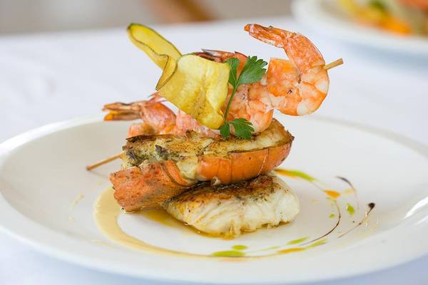 Gegrillter Hummer und Fisch auf einem weißen Teller im Le Duc de Praslin Hotel & Villas.