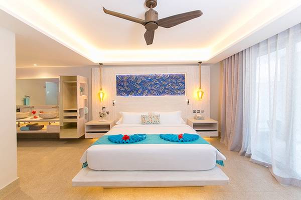 Schlafzimmer im Le Duc de Praslin Hotel & Villas mit einem großen Bett, Deckenventilator und offenem Badezimmer.