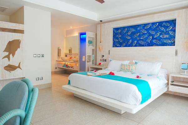 Schlafzimmer des Le Duc de Praslin Hotel & Villas mit Doppelbett, Nachttischen und Wanddekoration.