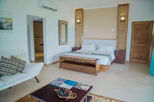 Schlafzimmer im Le Duc de Praslin Hotel mit Doppelbett, Sofa und Dekor.