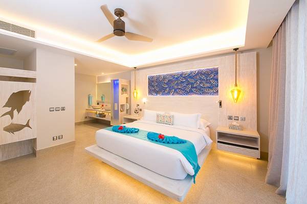 Schlafzimmer im Le Duc de Praslin Hotel & Villas mit großem Bett, Fisch-Dekor und moderner Einrichtung.