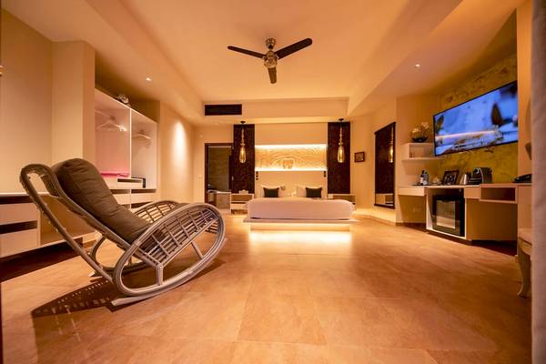 Schlafzimmer des Le Duc de Praslin Hotel mit Bett, Fernseher, Schrank und Liegestuhl.