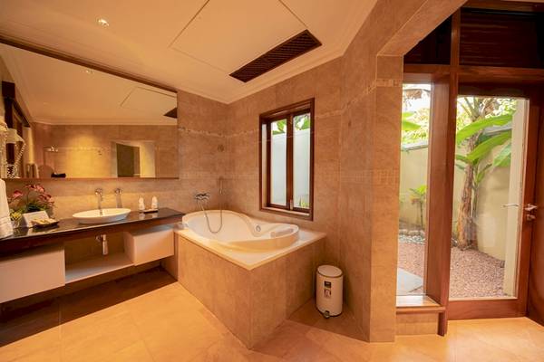 Badezimmer im Le Duc de Praslin Hotel & Villas mit Badewanne, Waschbecken und Spiegel.