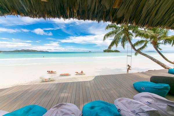 Le Duc de Praslin Hotel & Villas Strand mit Lounge-Sesseln und einer Frau auf einer Schaukel