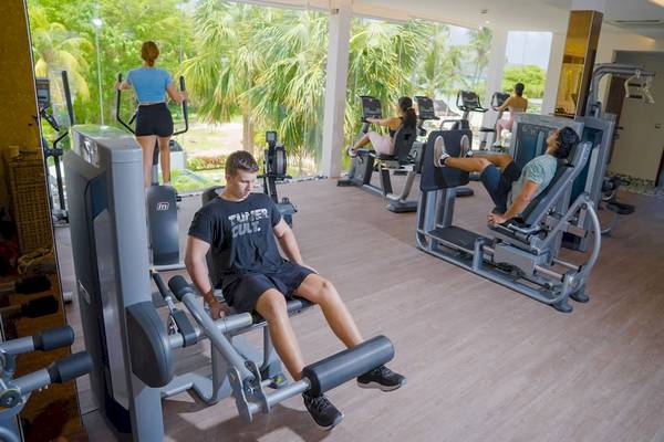 Fitnessbereich im Le Duc de Praslin Hotel mit mehreren Personen, die an verschiedenen Geräten trainieren.