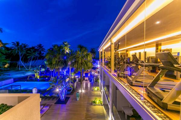 Nachtansicht des Fitnessbereichs des Le Duc de Praslin Hotel & Villas mit blauen Lichtern und Fitnessgeräten.