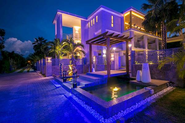 Nachtansicht des Le Duc de Praslin Hotel & Villas mit blauen Lichtern und Wasserfeature.