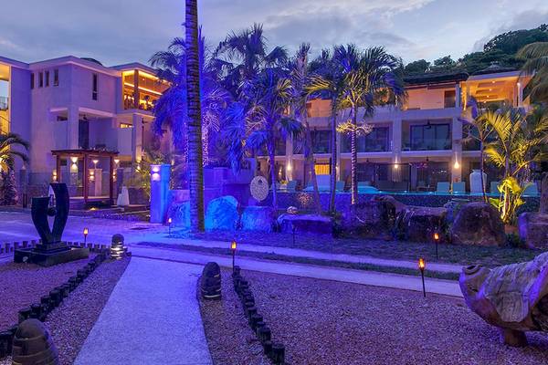 Nachtansicht des Le Duc de Praslin Hotel & Villas mit blauen Lichtern und tropischen Pflanzen.