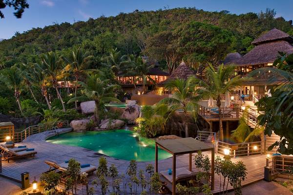 Außenansicht des Constance Lemuria Seychelles Hotels bei Nacht mit Swimmingpool und Loungebereich.