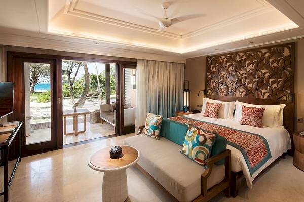 Schlafzimmer im Constance Lemuria Seychelles Hotel mit Bett, Couch und Terrassentüren zum Meer.