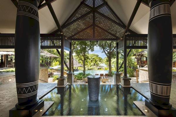 Innenbereich des Constance Lemuria Seychelles Hotels mit Pool und Blick auf den Ozean.