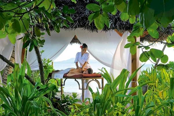 Massage-Therapeutin, die eine Massage in einem Garten unter einer Strohhut bietet.