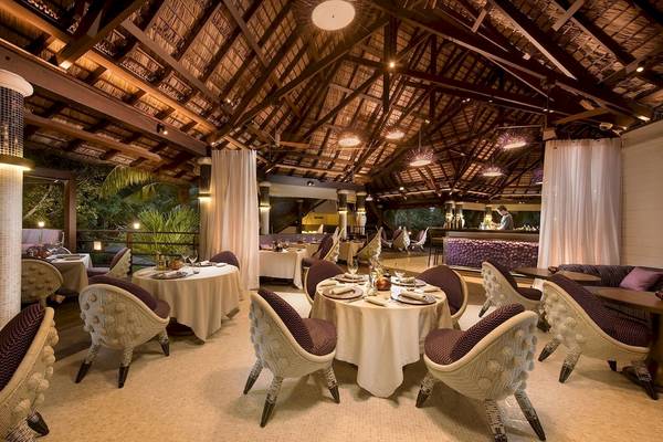 Innenbereich des Constance Lemuria Seychelles Restaurants mit modernen Möbeln und einer Theke.