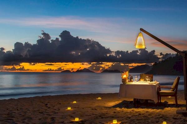 Romantisches Essen am Strand des Anantara Maia Seychelles Villas bei Sonnenuntergang.