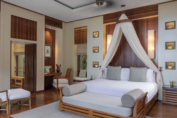 Schlafzimmer im Anantara Maia Seychelles Villas mit Doppelbett, Holzmöbeln und modernen Annehmlichkeiten.