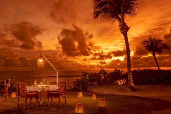 Dinnertisch am Strand im Anantara Maia Seychelles Villas bei Sonnenuntergang.
