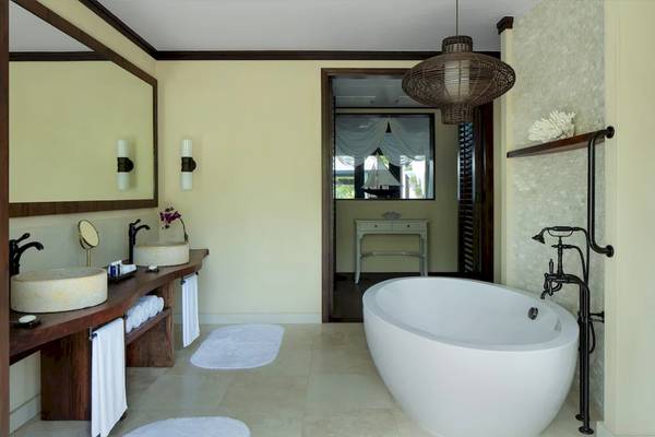 Badezimmer im STORY Seychelles Hotel mit Badewanne, Waschbecken und Spiegeln.