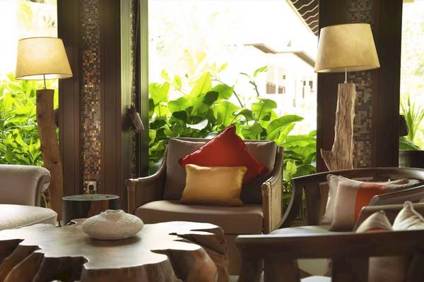 Loungebereich des STORY Seychelles Hotels mit Sofas und einem Tisch, umgeben von Pflanzen und Lampen.