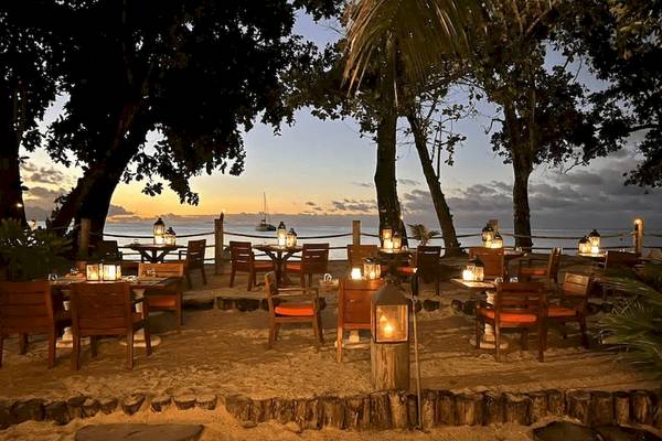 Außenbereich des STORY Seychelles Hotels mit abendlichen Tischarrangements am Strand