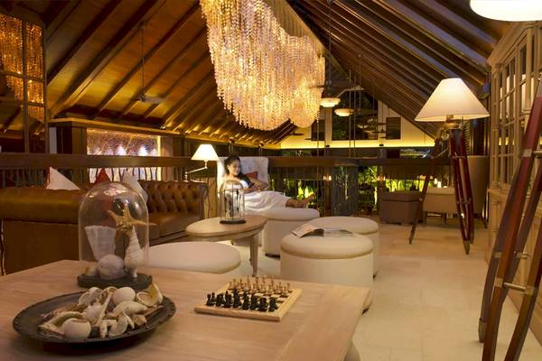 Loungebereich im STORY Seychelles Hotel mit Couch, Spielbrett und Deckenleuchte.