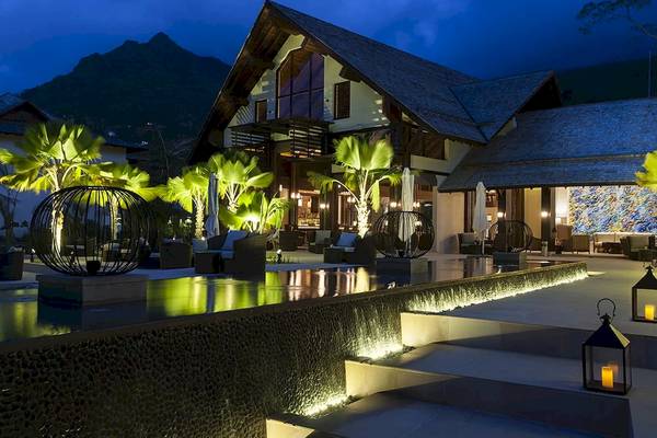 Außenbereich des STORY Seychelles Hotels bei Nacht mit Beleuchtung und Möbeln.