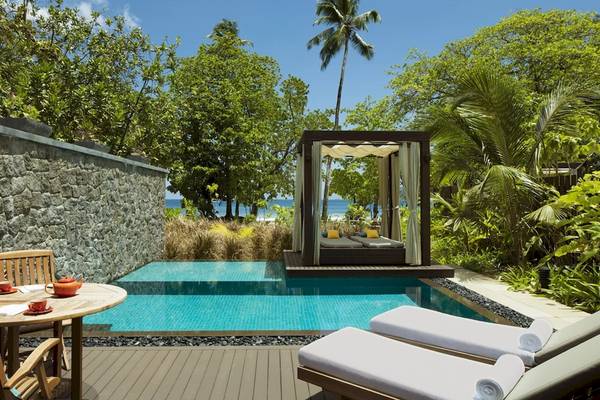 Pool-Loungebereich im STORY Seychelles Hotel mit zwei Liegen und einem Tisch.