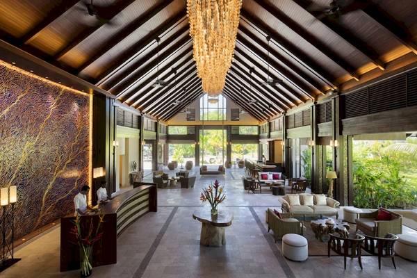 Empfangshalle des STORY Seychelles Hotels mit großen Kronleuchter und modernen Möbeln.