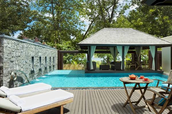 Außenpoolbereich des STORY Seychelles Hotels mit Loungeliegen, Tisch und Teekannen
