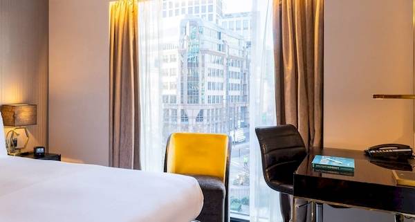 Das elegante Zimmer im Saint Hotel in London mit einem großen Bett, Schreibtisch und Stadtblick.