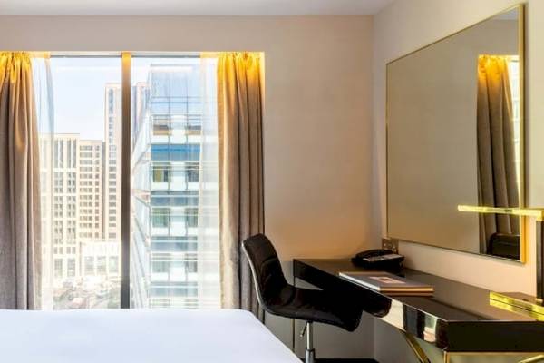 Ein modernes Hotelzimmer im Saint Hotel in London mit einem großen Bett, Schreibtisch und Blick auf die Stadt.