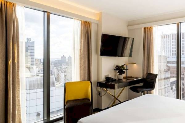 Innenansicht eines Zimmers im Saint Hotel in London mit Schreibtisch, Fernseher und Stadtblick.