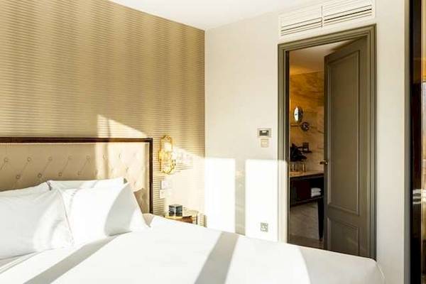 Schlafzimmer im Saint Hotel, London mit hellem Dekor, weißen Kissen und einem offenen Badezimmer.