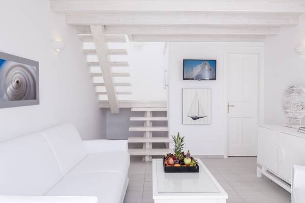 Wohnzimmer des Archipelagos Hotels mit weißem Sofa, Früchtetablett und Treppe.