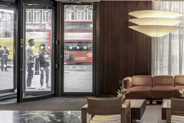 Lobby des Saint Hotels in London mit braunem Sofa, Couchtischen und Pflanzen.