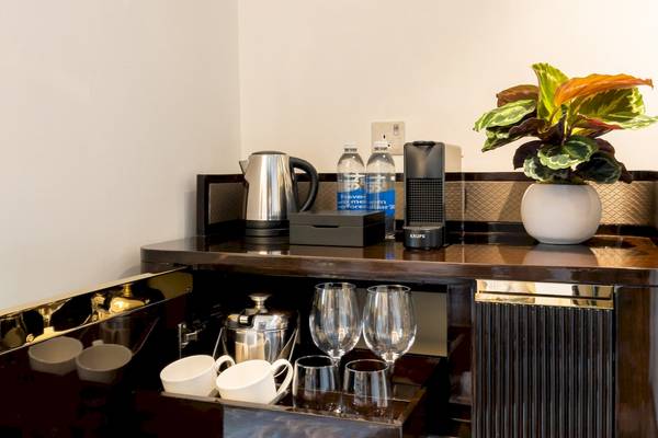 Barbereich des Saint Hotels in London mit Kaffeemaschine, Wasserflaschen, Krug, Gläsern und Pflanze.