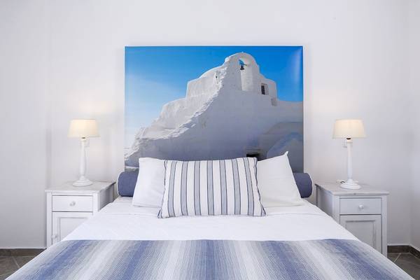 Doppelbett im Schlafzimmer mit weißem Wandbild, das eine Kirche zeigt