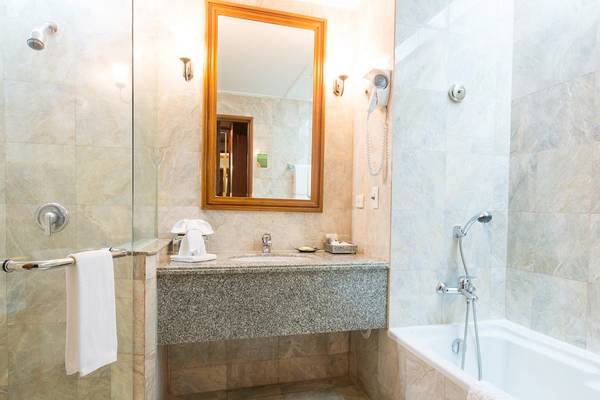 Badezimmer im Century Park Hotel mit einer Dusche, Badewanne, Waschbecken und Spiegel.