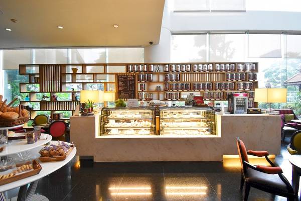 Innenansicht des Cafés im Century Park Hotel mit einer Theke, Vitrinen und Tischen.