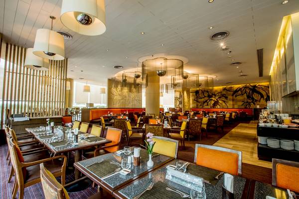 Innenbereich des Century Park Hotels mit vielen Tischen und Stühlen, goldenen Pendelleuchten und Holzboden.