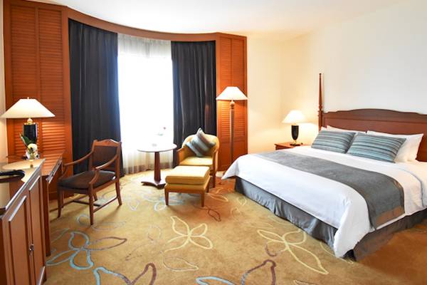 Schlafzimmer im Century Park Hotel mit einem großen Bett, zwei Nachttischen, Lampen und einem Fenster.