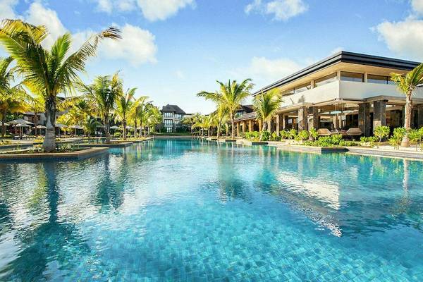 Außenpool im Westin Turtle Bay Resort & Spa, Mauritius, mit Gebäuden und Palmen.