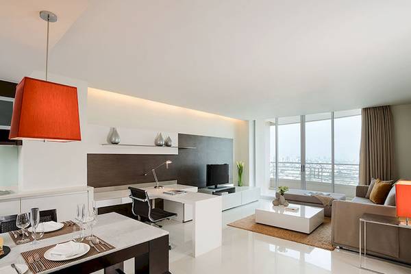 Inneneinrichtung des JC Kevin Sathorn Bangkok Hotels mit Esstisch, Sofa und Fernseher.