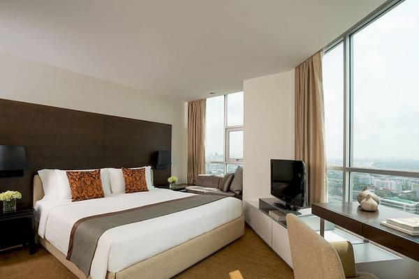 Hotelzimmer im JC Kevin Sathorn Bangkok mit großem Bett, Fernseher und Ausblick auf die Stadt.