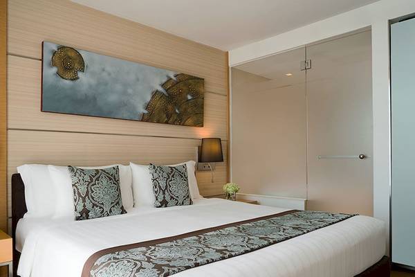 Schlafzimmer im JC Kevin Sathorn Bangkok Hotel mit großem Bett, Dekor und Gemälde an der Wand.